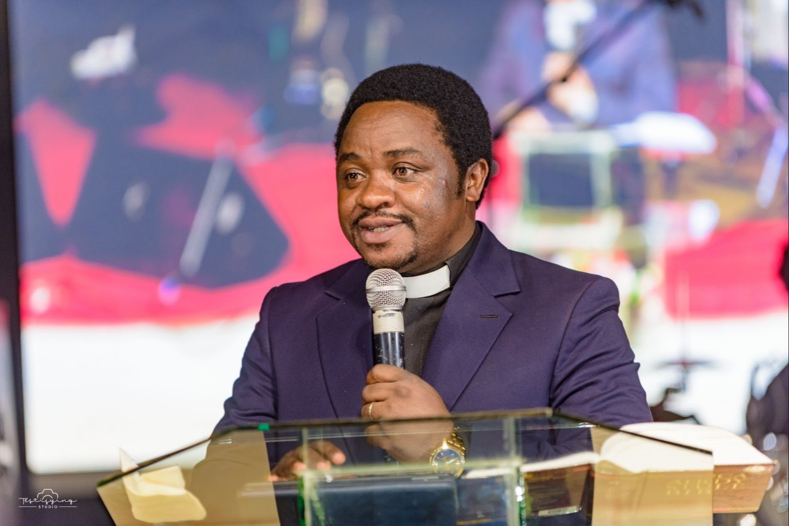 Rev. Dr. Ngi Gideon, Vice-Chancellor of GHITS University, speaking at a podium in a formal suit